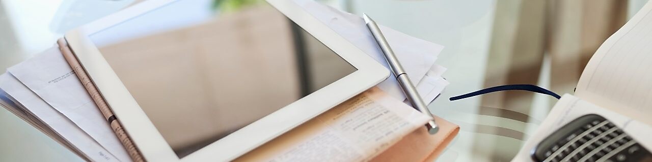 Tablet computer, newspaper, coffee cup and cell phone on desk