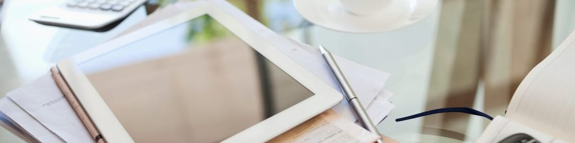 Tablet computer, newspaper, coffee cup and cell phone on desk