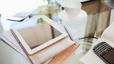 Tablet computer, newspaper, coffee cup and cell phone on desk